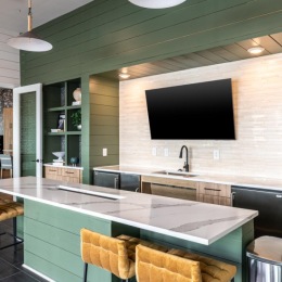 a kitchen with a bar chairs and tv